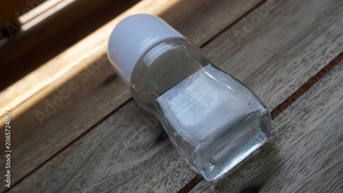 Foto Clear roll-on deodorant bottle lying on side on wooden surface in soft natural light