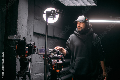 The director of photography holds a camera in his hands on the set in the pavilion. A professional videographer films a movie, commercial or TV series in a studio.