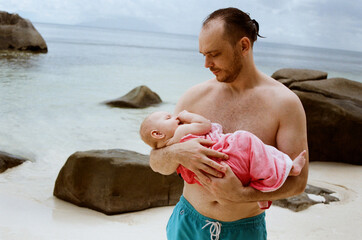 Father holding baby at the beach on a sunny day