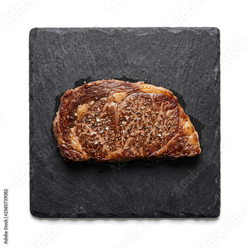 Grilled ribeye steak piece served on dark slate stone board