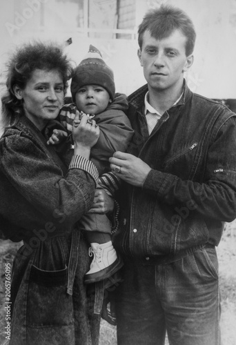 Bild auf Leinwand Authentic vintage family portrait with young parents and toddler outdoors