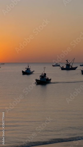 Fishing boats sailing on calm ocean at vibrant sunset, cinematic wide shot, silhouettes against golden sky, symbolizing livelihood, marine industry, and peaceful journey