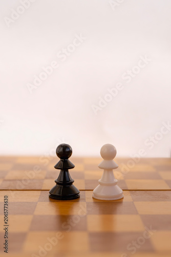 Obraz na płótnie Black and white chess pawn pieces facing each other on chessboard, ordinary employees competition concept