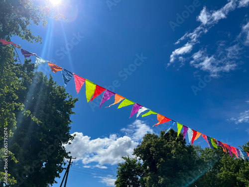A bright garland of multicolored flags against a summer blue sky.