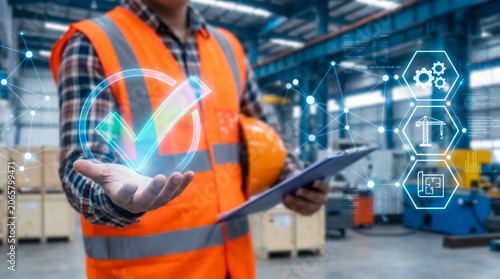 Industrial engineer holding a digital checkmark icon with factory background and construction planning interface