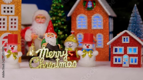 In the Christmas town, in front of the colorful houses, there are snowmen with letters and Santa Claus with a gnome
