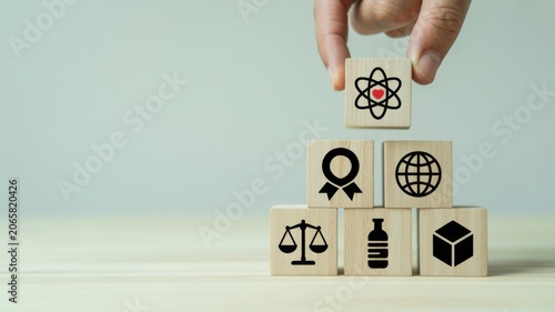 Hand placing atomic symbol block on top of global business and law icons