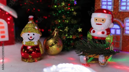 Between the houses there is a snowman with a small ball and Santa Claus on a sleigh