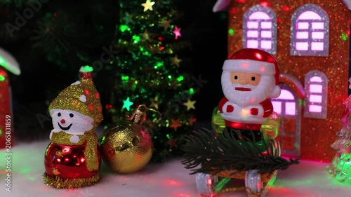 In front of the houses there are snowmen with a yellow ball and Santa Claus on a sleigh