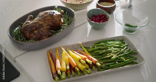 Camera is sliding up and right, revealing roast chicken, carrots, sauce, faucet, displaying meal