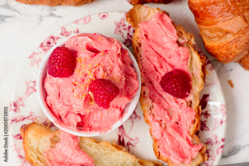 Raspberry butter spread on fresh croissants