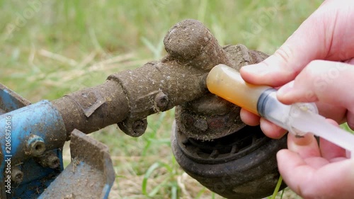 Man Lubricating Gearbox of Gas Powered String Trimmer During Maintenance
