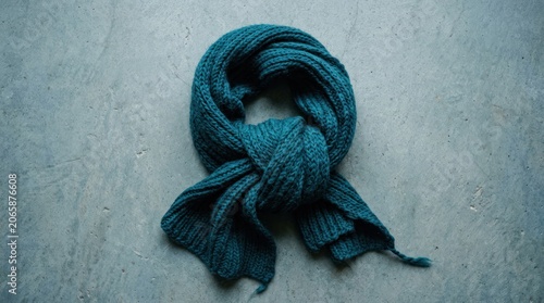 Knitted Teal Scarf Tied in a Knot on a Textured Background.