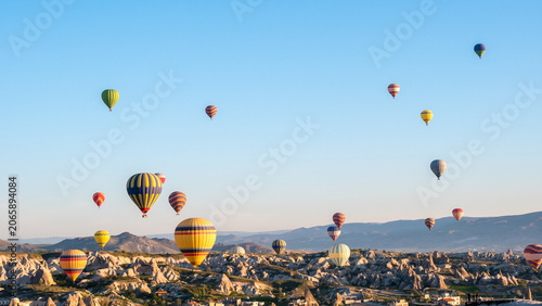 Many colorful hot air balloons flying over Cappadocia valley at sunrise
