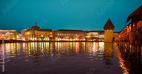 Tableau sur toile Beleuchtete Kapellbrücke mit Wasserturm und Uferpromenade in Luzern bei nächtlic