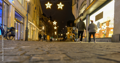 Blick über das Kopfsteinpflaster der beleuchteten Kapellgasse in Luzern mit weihnachtlicher Sternenbeleuchtung bei Nacht