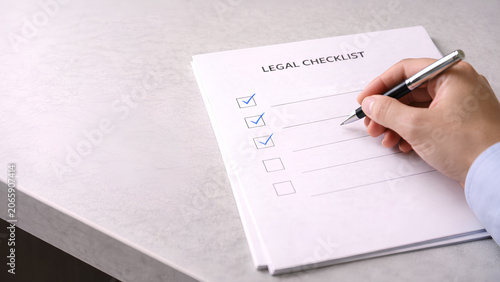 hand holding pen checking boxes on legal checklist document close up