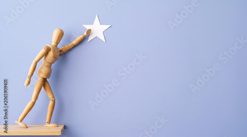 Employee achievement and career success goal concept with wooden mannequin reaching for star for mid-year performance review presentation background