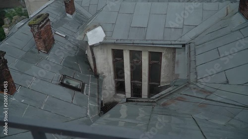 A view of the roof of an old architectural building with a hidden window, brick chimneys, slate, and tiles. A walk through the old part of the tourist town.