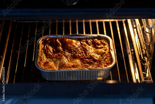 Ready meal baking in disposable aluminum foil tray inside oven