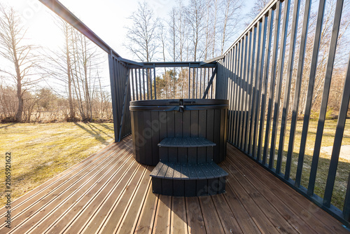 Foto Compact round hot tub on deck with matte black slatted railings