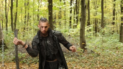 Nordic warrior, Black attire, Autumn warrior. In autumnal forest, bearded Viking warrior dressed in black is holding axe.