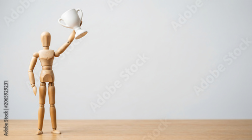 Employee performance review success and KPI tracking growth concept with wooden mannequin holding trophy cup with copy space for business presentation banner