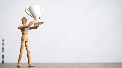 Mid-year performance reviews and KPI tracking concept with a wooden mannequin holding a white trophy cup with copy space for business growth analysis presentation banner