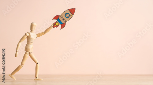 Mid-year performance review and business growth concept with wooden mannequin launching a colorful rocket with copy space for company presentation slide