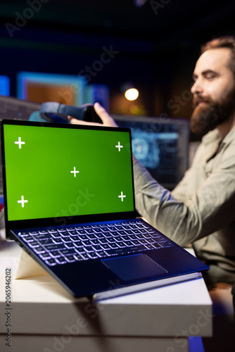 Photography Programmer updating artificial intelligence algorithm using green screen laptop, making it become sentient