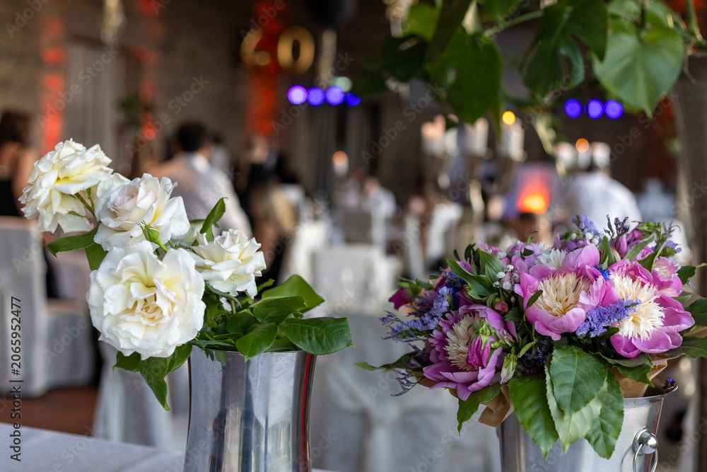 Obraz premium Celebration setting with flower arrangements on tables and guests enjoying their time together at a venue during evening hours