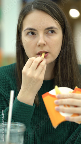 woman eating french fries and cola at the food court.