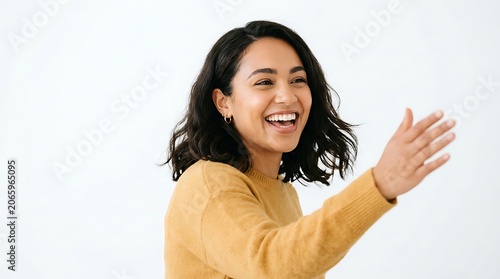 Smiling young woman with dark hair wearing yellow sweater isolated on white background