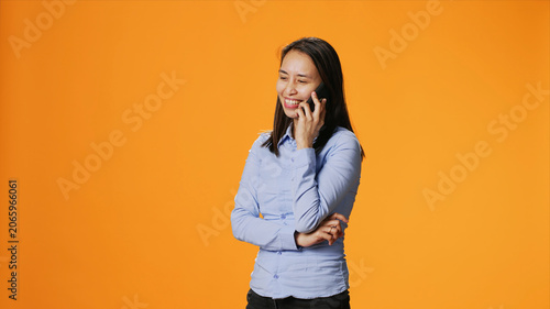 Photography Casual adult receiving phone call in front of camera, chatting with friends on smartphone telecommunications network, Asian girl answering telephone for remote discussion in studio