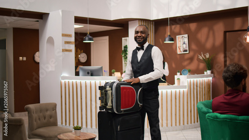 Konstfotografi African American bellboy takes suitcases to help important guest with room accom
