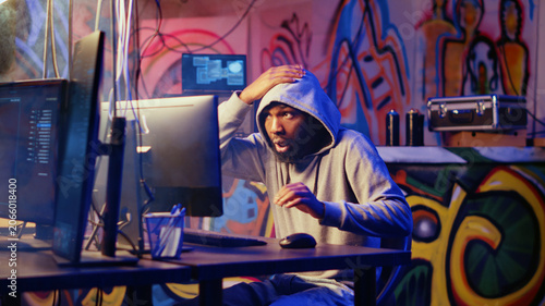 Fotografie Hacker in graffiti painted hideout interrupted by police sirens from writing malware code on computer, running to escape before getting caught, criminal den found by anti hacking law enforcement