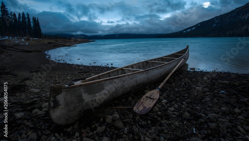Decked expedition canoe with a wooden paddle on a shore of Carter Lake winter dusk after paddling