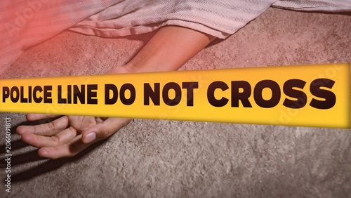 Crime scene concept with a dead body lying on the ground covered by a cloth, behind a yellow tape with the text POLICE LINE DO NOT CROSS.