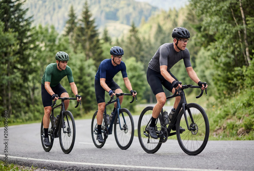 Group of three male cyclists riding road bikes on mountain highway