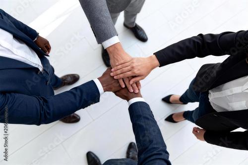 High angle view of diverse business team stacking hands together on white floor, multiracial partnership, corporate unity and connection concept