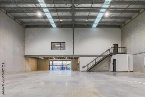 Foto Modern industrial warehouse interior featuring high clearance ceilings, mezzanine office space, concrete flooring and contemporary construction