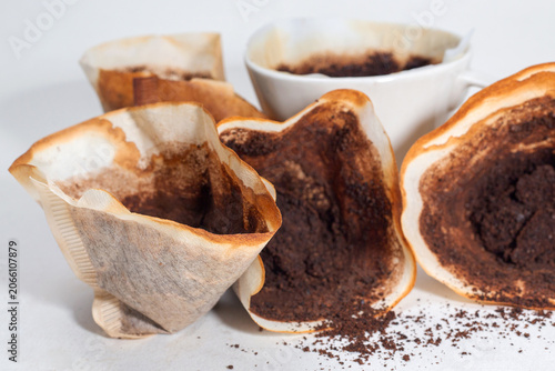 Drip black coffee with coffee filter and coffee grounds on a white background.