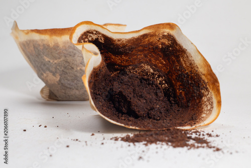 Drip black coffee with coffee filter and coffee grounds on a white background.