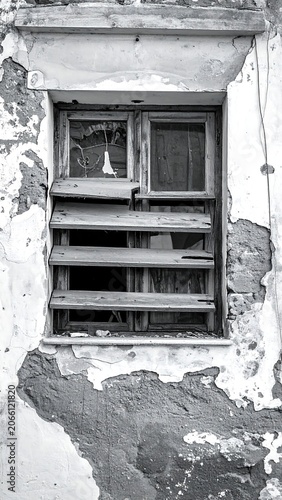 A black-and-white photo of a weathered window on a dilapidated wall with peeling paint