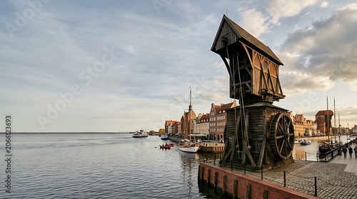 Historic wooden port crane on a riverfront in a scenic city