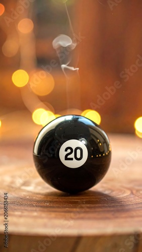 A black pool ball with the number 20 on a wooden surface