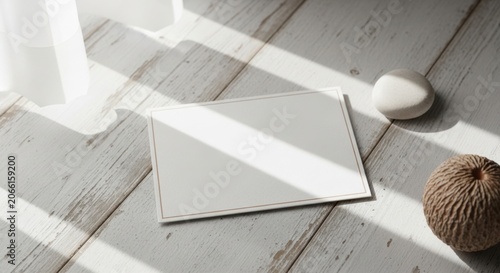 Blank card on light wood floor with natural sunlight and textured objects