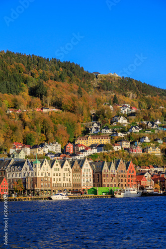 Panorama of Bergen Port with hanseatic buildings of World Heritage Site Bryggen, boats and mountain Fløyen with funicular railway Fløibanen in autumn in Norway