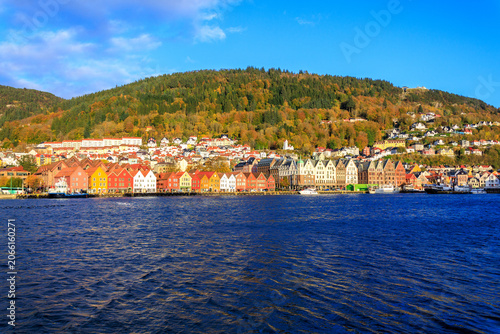 Panorama of Bergen Port with colorful wooden hanseatic buildings of World Heritage Site Bryggen, boats and mountain Fløyen with funicular railway Fløibanen in autumn in Norway