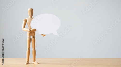Mid-year performance review and constructive feedback concept with wooden mannequin holding blank speech bubble with copy space for corporate employee evaluation presentation slide